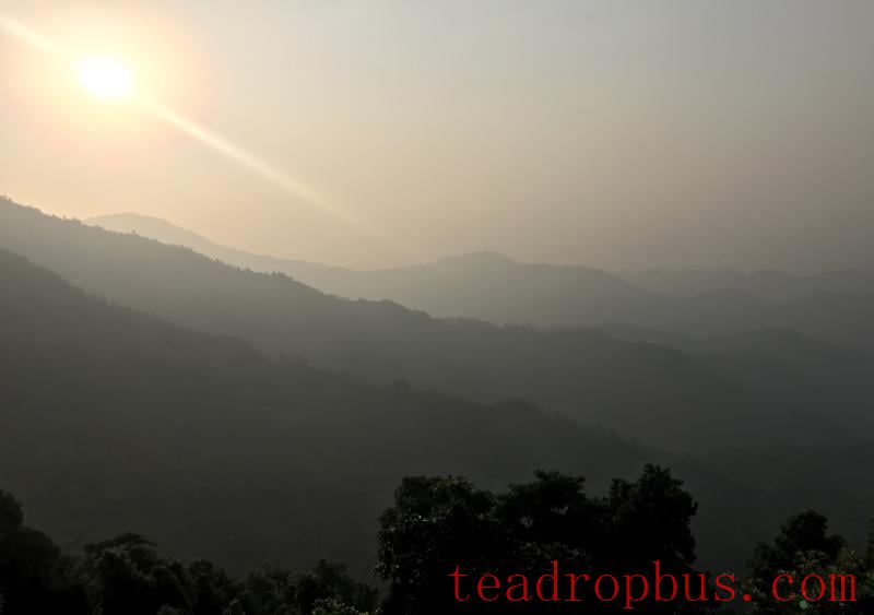 Sun rises against the hills of Darjeeling at Jungpana Tea Estate appearing in silhouette against the morning rays
